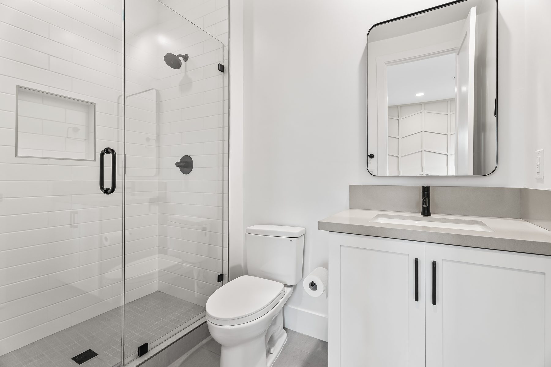 Guest bathroom with frameless glass shower, black fixtures, and quartz vanity in Arcadia, Phoenix