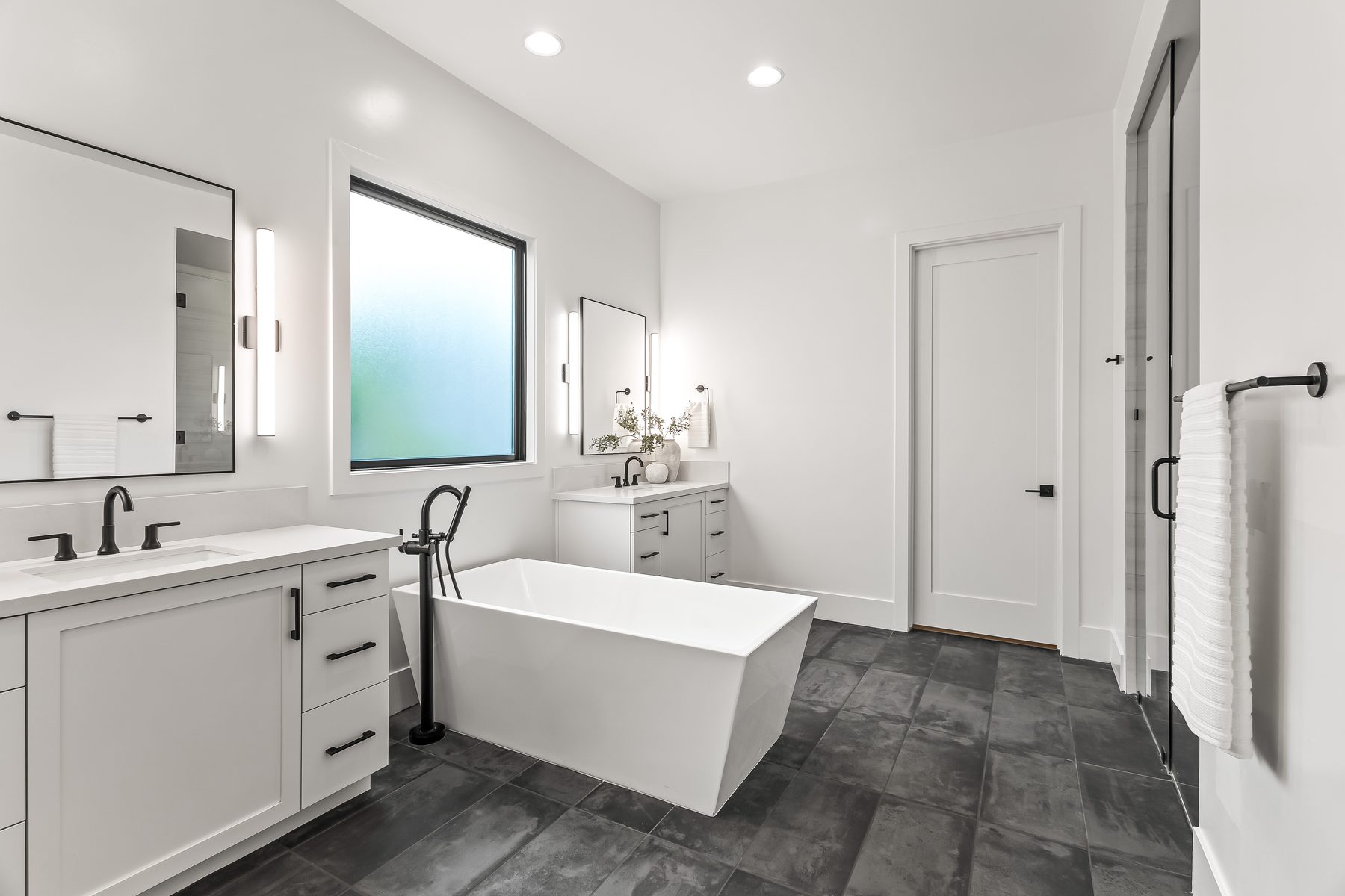 Primary bathroom with freestanding tub, double vanity, and dark tile floor in Lower Arcadia