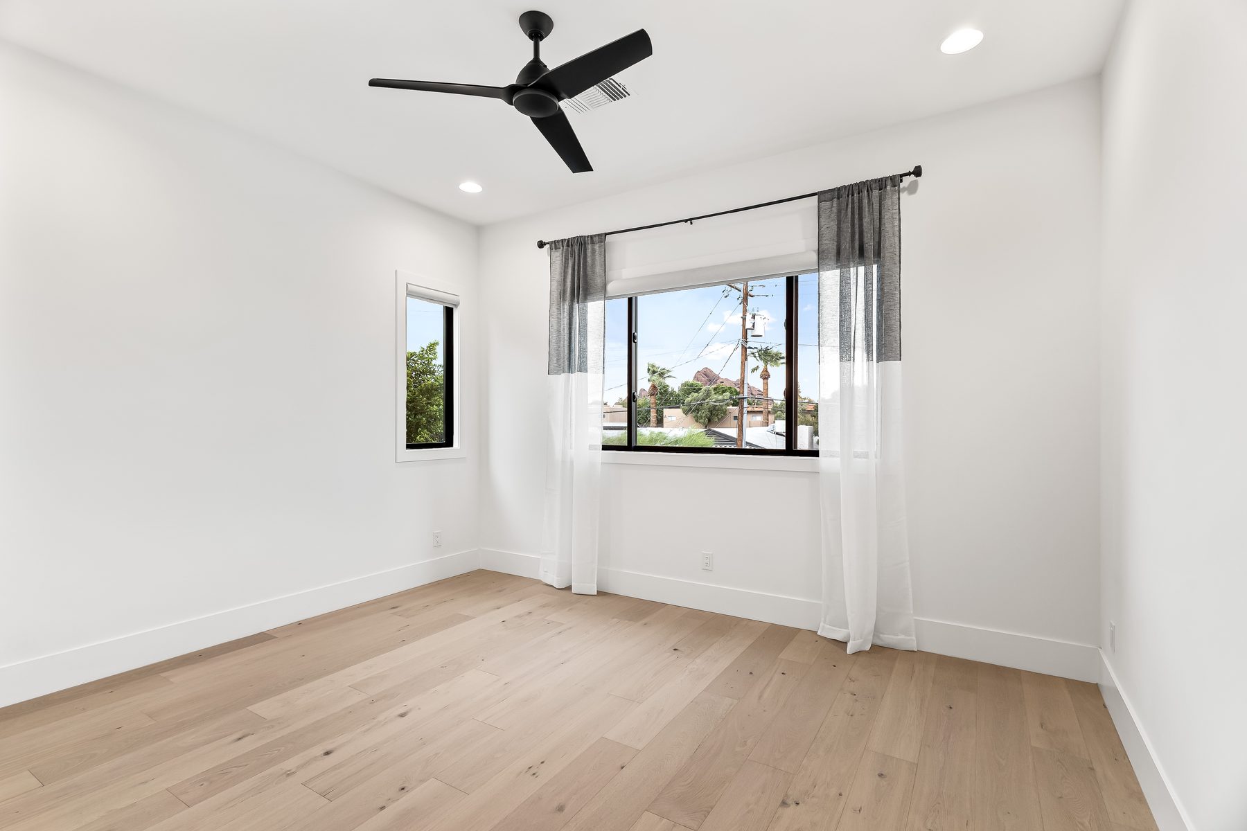 Second-level bedroom with ceiling fan, oak flooring, and windows at 5513 E Verde Lane